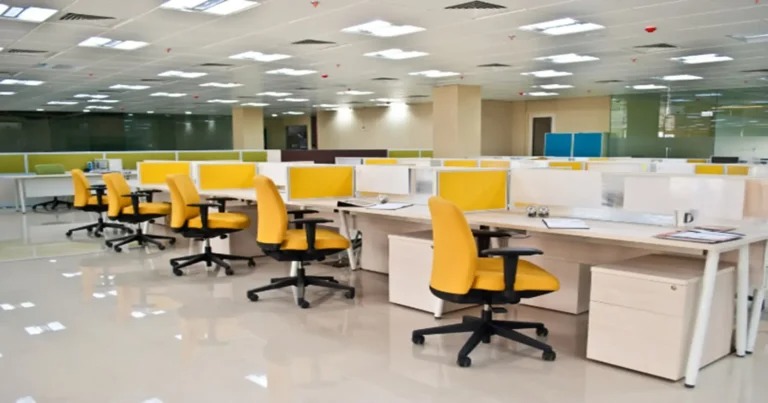Spacious open-plan tech office with floor-to-ceiling glass, bright daylight, white walls and minimalist workstations